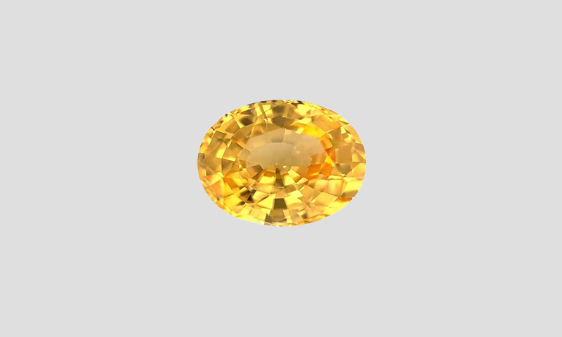 vivid yellow cushion cut sapphire on a dark background